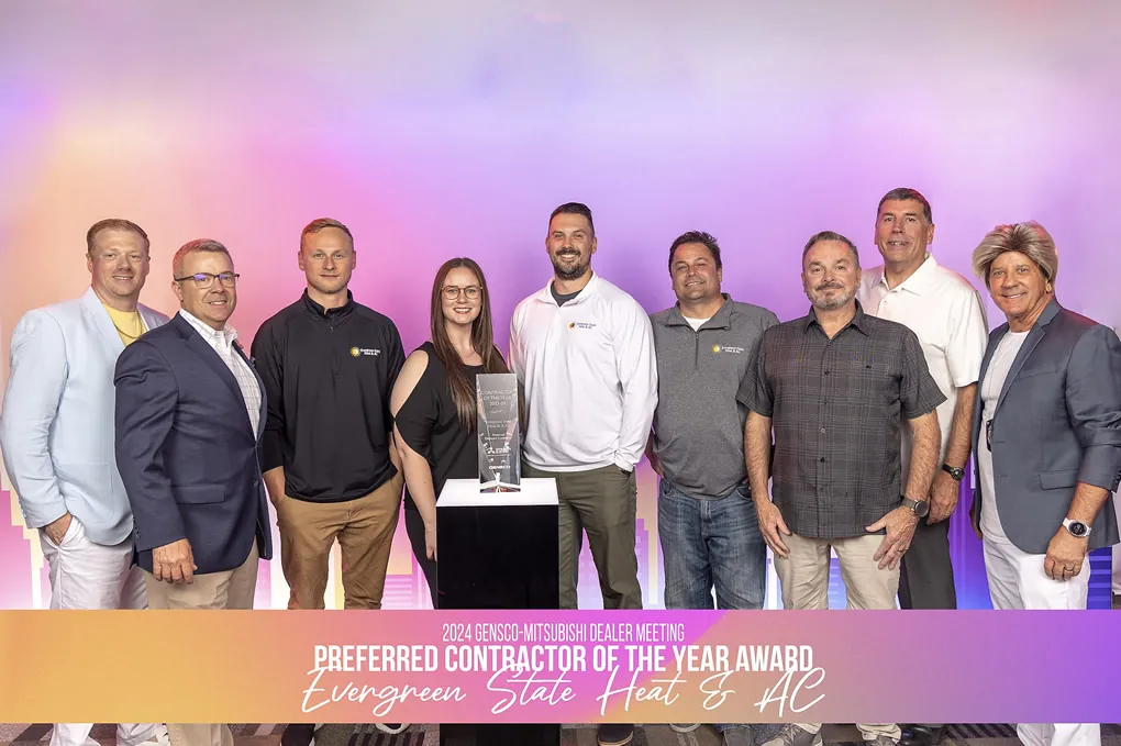 Nine people stand smiling behind an award trophy on a pedestal, in front of a colorful backdrop with text about our team getting the 2024 preferred contractor of the year award for Evergreen State Heat & AC. Evergreen State Heat & AC